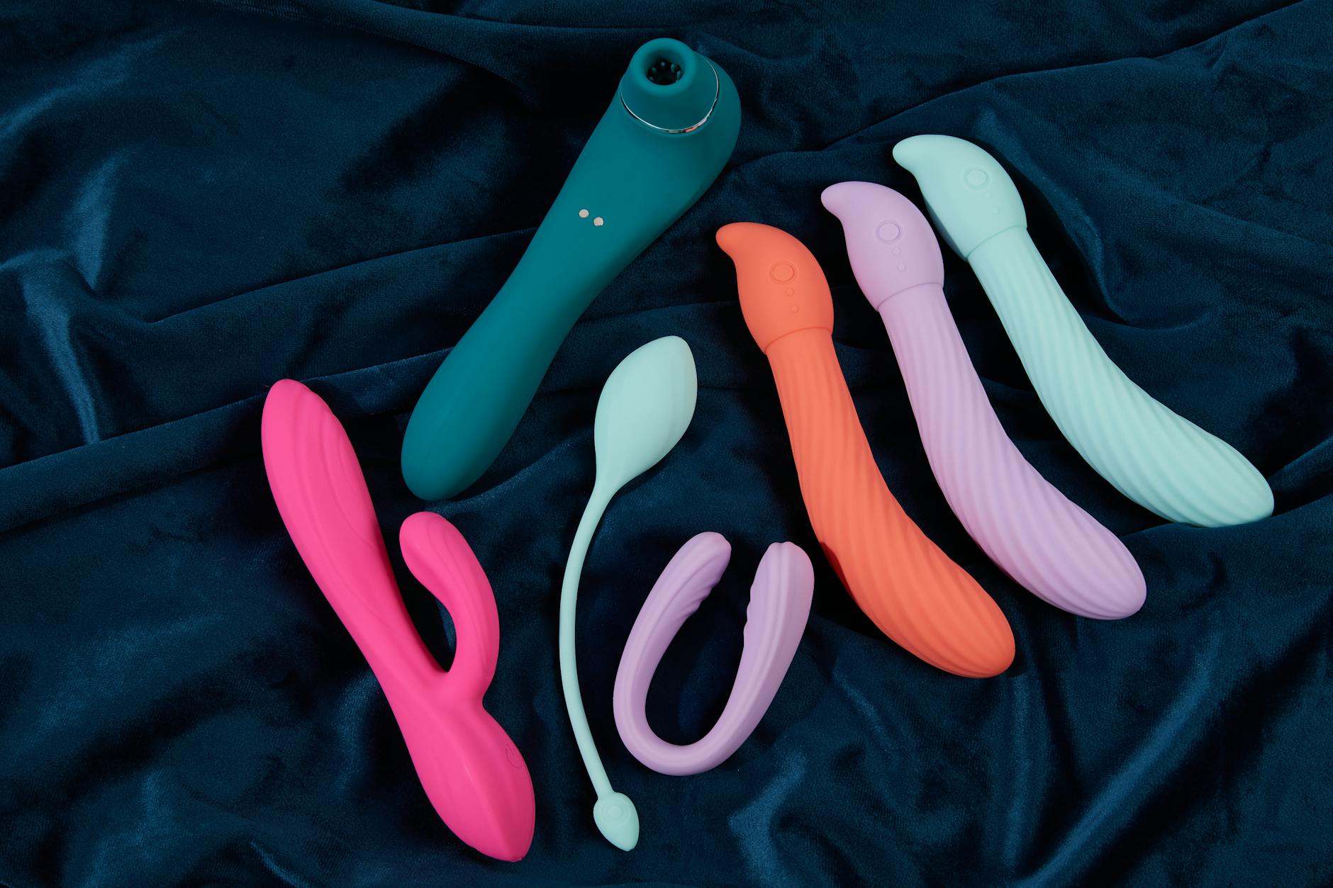 A yellow silicone vibrator surrounded by fresh fruit on a bright background