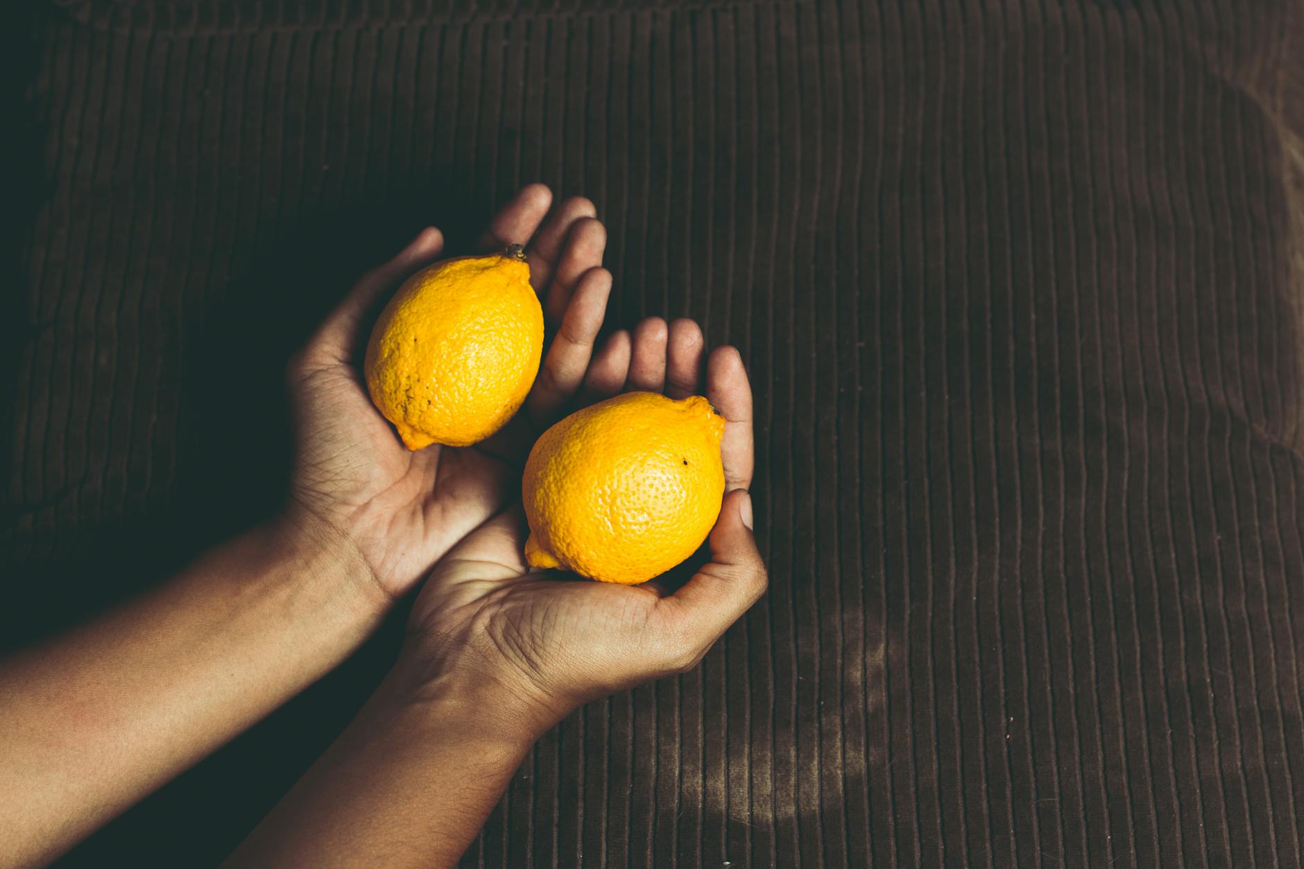 Two hands cupping fresh lemons together, symbolizing shared connection and intimacy