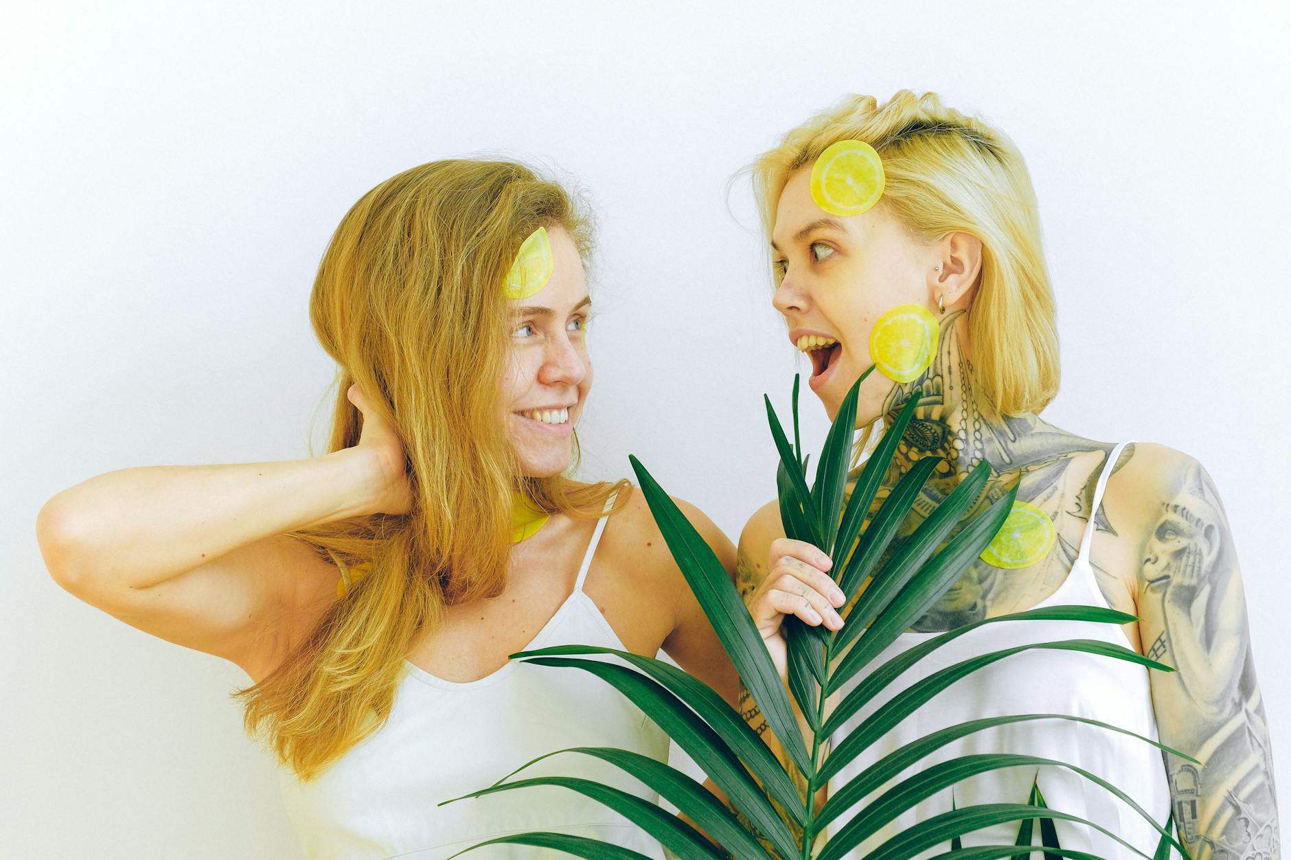 Two women laughing together with lemon slices, expressing joy and fun