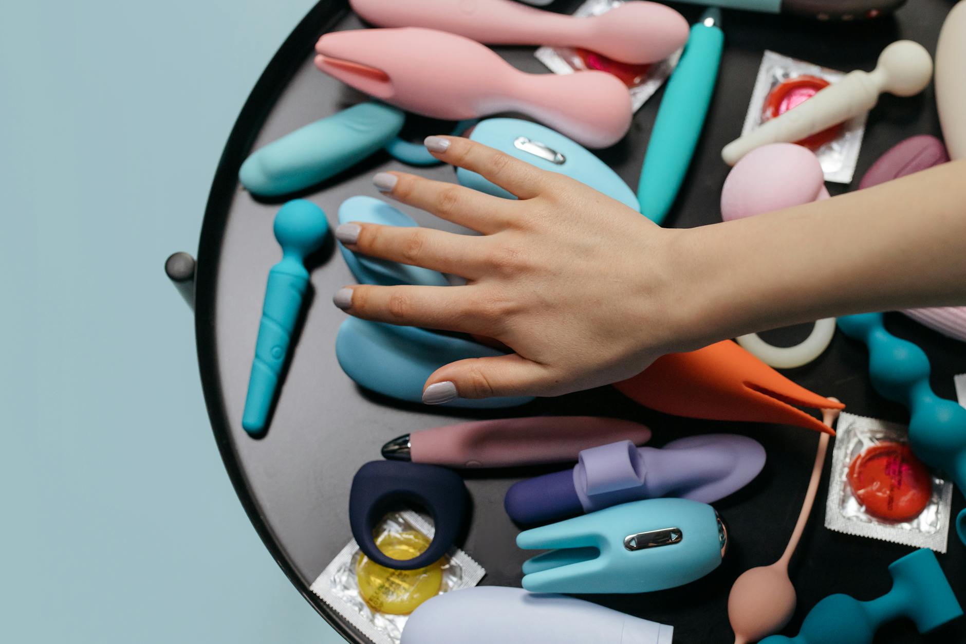 Woman holding colorful clitoral vibrators with a thoughtful expression