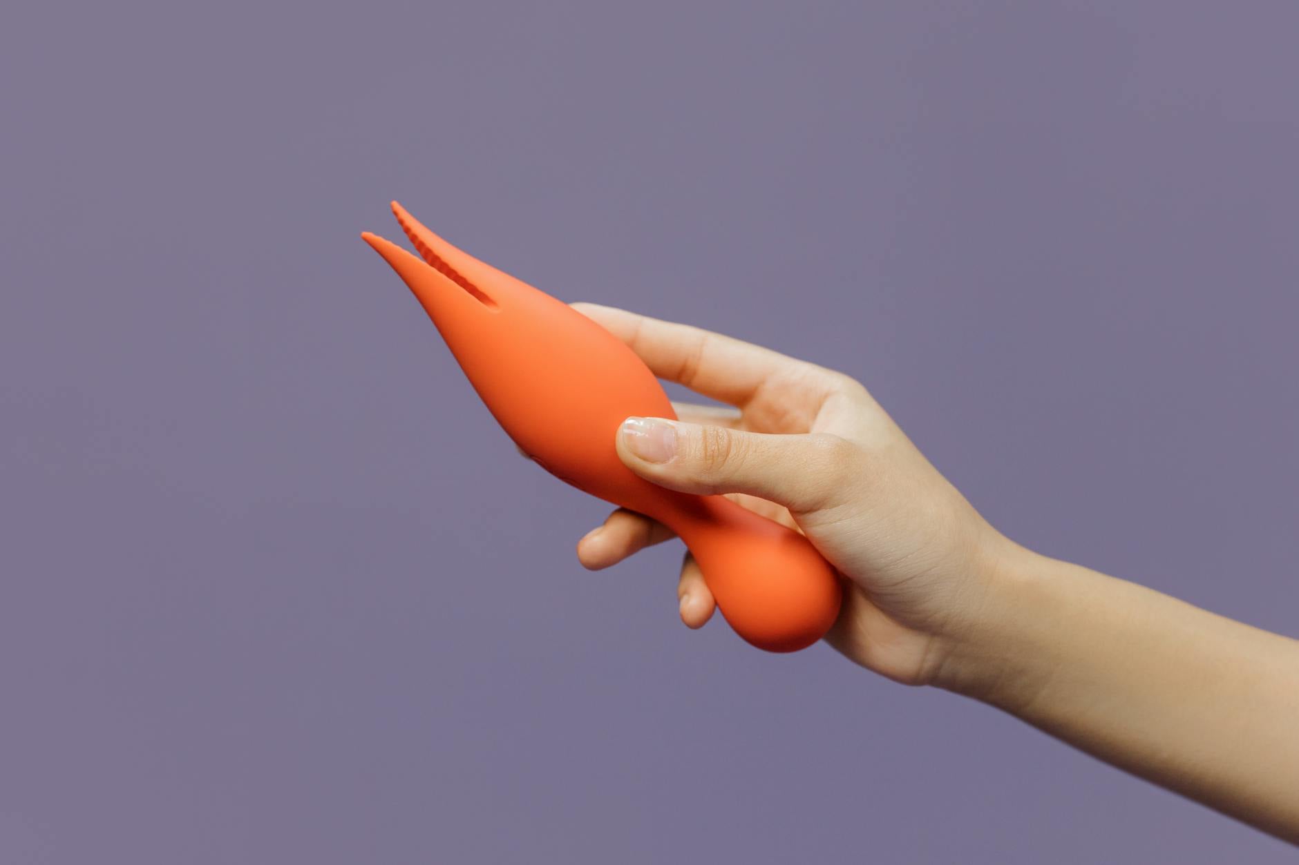 Hand holding a vibrator against a minimalist backdrop, representing modern pleasure exploration.
