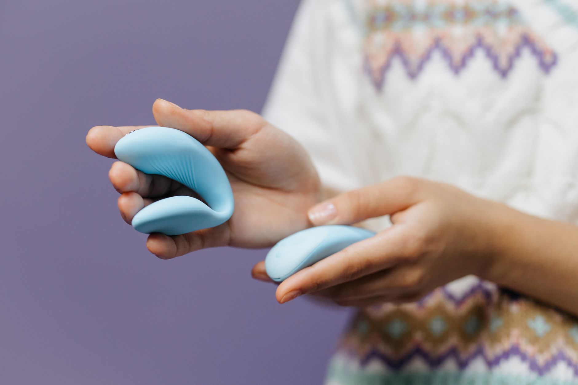 A hand holding a sleek blue vibrator against a purple background, representing reclaiming pleasure during antidepressant use.