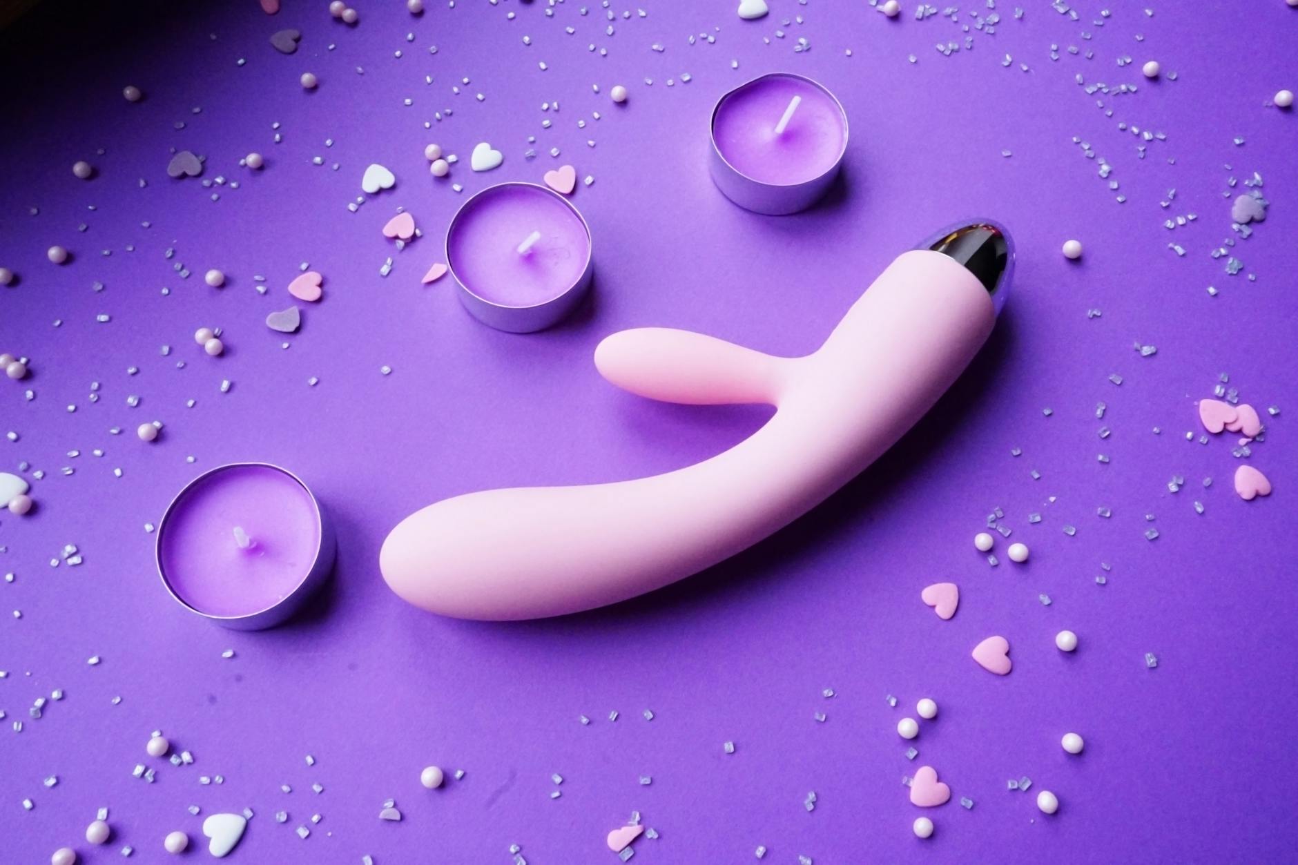Vibromasseur rose et violet sur fond avec confettis et bougies