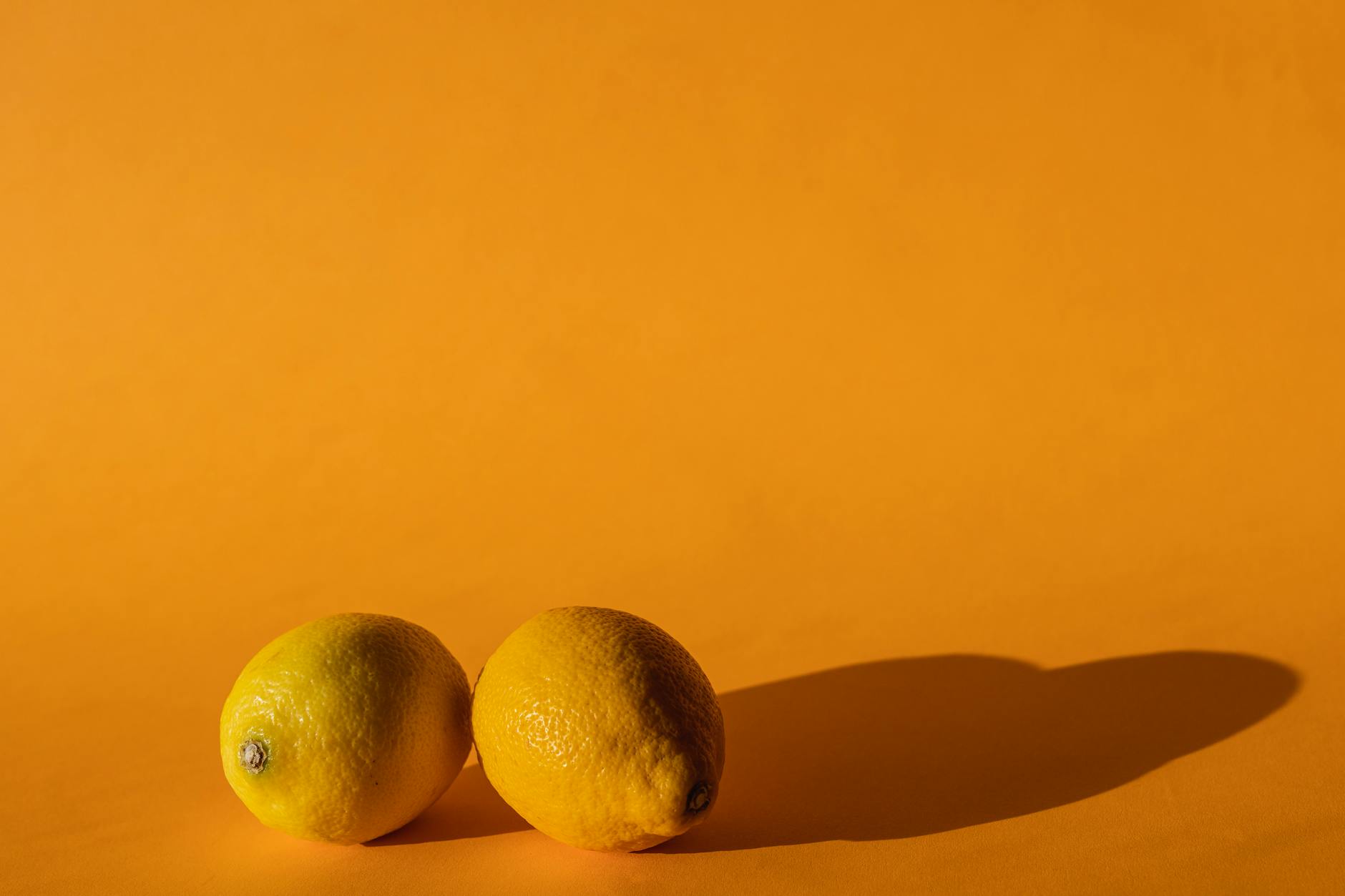 Blue vibrator surrounded by flowers and citrus on warm yellow background
